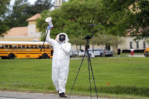 Lance Knippers protests outside as congregants arrive for services at the Life Tabernacle Church in Central, La., Sunday, March 29, 2020. Pastor Tony Spell has defied a shelter-in-place order by Louisiana Gov. John Bel Edwards, due to the new coronavirus pandemic, and continues to hold church services with hundreds of congregants. (AP Photo/Gerald Herbert)