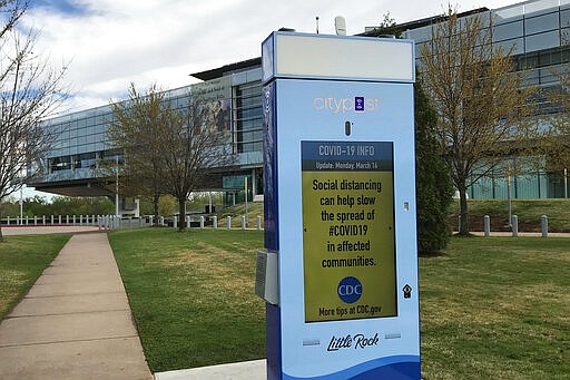 In this Sunday, March 29, 2020 photo, a video screen outside the Clinton presidential library in Little Rock, Ark., includes guidance about social distancing. (AP Photo/Andrew Demillo)