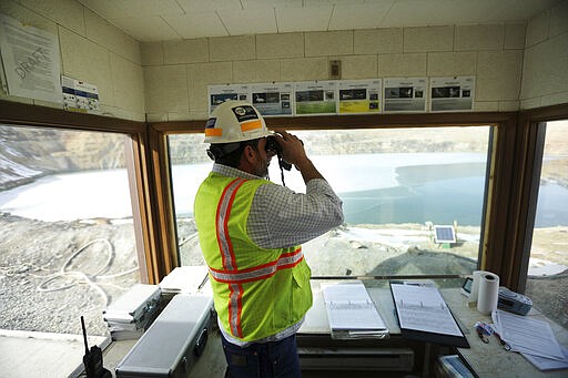 In this March 5, 2020, photo, Mark Thompson, the environmental affairs manager for Montana Resources, scans the water at the Berkeley Pit in Butte, Montana. The Trump administration is moving to scale back criminal enforcement of a century-old law protecting most American wild bird species. Thompson said it would keep up the efforts that drive away almost all birds regardless of the Trump administration&#146;s actions, mirroring pledges from some other companies and industries. (Meagan Thompson/The Montana Standard via AP)