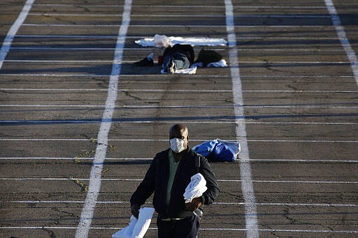 Boxes painted on the ground of a parking lot mark places for people to sleep at a makeshift camp for the homeless Monday, March 30, 2020, in Las Vegas. Officials opened part of a parking lot as a makeshift homeless shelter after a local shelter closed when a man staying there tested positive for coronavirus. (AP Photo/John Locher)