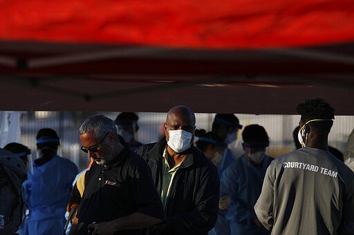 People wait in line to enter a makeshift camp for the homeless Monday, March 30, 2020, in Las Vegas. Officials opened part of a parking lot for the camp after a local shelter closed when a man staying there tested positive for the coronavirus. (AP Photo/John Locher)