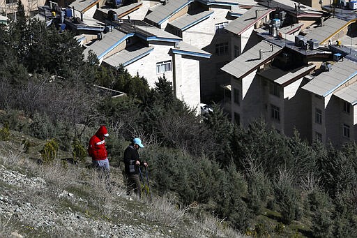 Hikers descend from a foothill of the Alborz mountain range, overlooking the capital Tehran, as they spend New Year, or Nowruz, holidays, Iran, Tuesday, March 31, 2020. In recent days, Iran which is battling the worst new coronavirus outbreak in the region, has ordered the closure of nonessential businesses and banned intercity travels aimed at preventing the virus' spread. Public parks are closed as well as sport and recreational clubs which were shut previously. (AP Photo/Vahid Salemi)