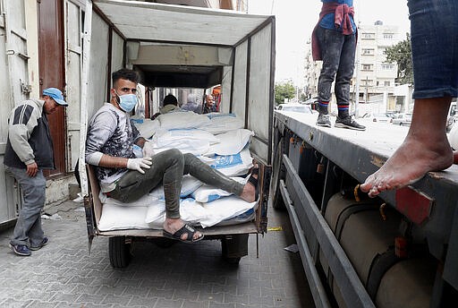 Palestinian workers load sacks of flour distributed by the United Nations Relief and Works Agency (UNRWA) on a tuk-tuk to distribute to poor refugee families at Sheikh Redwan neighborhood in Gaza City, Tuesday, March 31, 2020. The United Nations has resumed food deliveries to thousands of impoverished families in the Gaza Strip after a three-week delay caused by fears of the coronavirus. UNRWA, the U.N. agency for Palestinian refugees, provides staples like flour, rice, oil and canned foods to roughly half of Gaza&#146;s 2 million people. (AP Photo/Adel Hana)