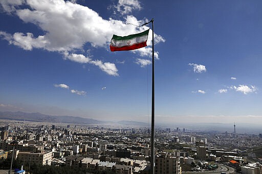 Iran's national flag waves in northern Tehran, Iran, Tuesday, March 31, 2020. In recent days, Iran which is battling the worst new coronavirus outbreak in the region, has ordered the closure of nonessential businesses and banned intercity travels aimed at preventing the virus' spread.  (AP Photo/Vahid Salemi)