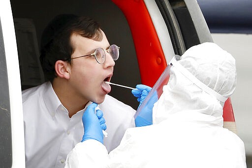 An ultra-Orthodox Jewish young man is tested for COVID-19 by medical personnel wearing protective gear as part of the government's measures to help stop the spread of the coronavirus in the orthodox city of Bnei Brak, a Tel Aviv suburb, Israel, Tuesday, March 31, 2020. The new coronavirus causes mild or moderate symptoms for most people, but for some, especially older adults and people with existing health problems, it can cause more severe illness or death. (AP Photo/Ariel Schalit)