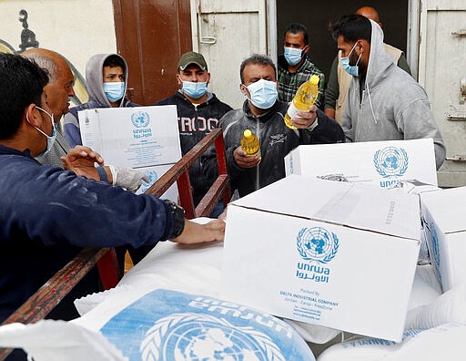 Palestinian workers load food supplies distributed by the United Nations Relief and Works Agency (UNRWA) at the Sheikh Redwan neighborhood of Gaza City, Tuesday, March 31, 2020. The United Nations has resumed food deliveries to thousands of impoverished families in the Gaza Strip after a three-week delay caused by fears of the coronavirus. UNRWA, provides staples like flour, rice, oil and canned foods to roughly half of Gaza&#146;s 2 million people. (AP Photo/Adel Hana)