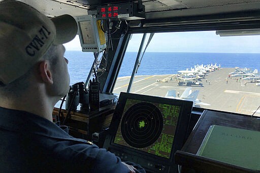 FILE - In this April 10, 2018, file photo, a U.S. Navy crewman monitors on the deck of the U.S. aircraft carrier Theodore Roosevelt in international waters off South China Sea. The USS Theodore Roosevelt made the second-ever visit by a U.S. aircraft carrier strike group to Vietnam to mark 25 years of diplomatic relations and growing security ties between the former Cold War antagonists amid China's aggressive moves in the South China Sea.  (AP Photo/Jim Gomez, File)