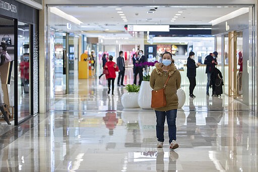 In this photo released by Xinhua News Agency, people wearing protective masks to prevent the new coronavirus outbreak walk on a re-opened shopping mall in Wuhan in central China's Hubei province on Monday, March 30, 2020. Shopkeepers in the city at the center of China's virus outbreak were reopening Monday but customers were scarce after authorities lifted more of the anti-virus controls that kept tens of millions of people at home for two months. (Fei Maohua/Xinhua via AP)