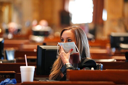 State Rep. Paula Davis, R-Dist. 69, holds a mask to her face as legislators convene in a limited number while exercising social distancing, due to the new coronavirus pandemic, at the State Capitol in Baton Rouge, La., Tuesday, March 31, 2020. They assembled briefly on the last day bills cold be introduced during the legislative session. (AP Photo/Gerald Herbert)