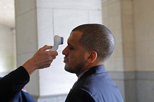 State Rep. Jason Hughes, D-Dist. 100, has his temperature taken as he arrives at the State Capitol in Baton Rouge, La., Tuesday, March 31, 2020. Legislators convened in limited numbers, while exercising social distancing due to the new coronavirus pandemic, on the last day bills could be introduced during the legislative session. (AP Photo/Gerald Herbert)