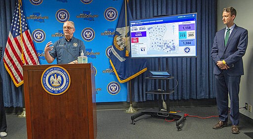 Observing social distancing, Dr. Alex Billioux, asst. state public health officer, right, watches as Gov. John Bel Edwards addresses steps being taken to fight the Coronavirus during a press conference at GOHSEP Monday March 30, 2020, in Baton Rouge, La. (Bill Feig/The Advocate via AP, Pool)