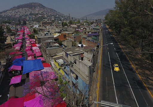 Pink tarps protect street stalls from the sun, as a reduced, but still active, street market takes place alongside a virtually deserted highway, in Mexico City, Sunday, March 29, 2020. In a little more than a week, Mexico has gone from seeing its president giving kisses and hugs at his events to the first firm call from the government for the populace to stay at home, due to the coronavirus. (AP Photo/Rebecca Blackwell)