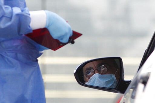 A doctor gathers information from a driver arriving to get tested for COVID-19 at private laboratory Biomedica de Referencia, in the Lomas Virreyes neighborhood of Mexico City, Thursday, March 26, 2020. The new coronavirus causes mild or moderate symptoms for most people, but for some, especially older adults and people with existing health problems, it can cause more severe illness or death. (AP Photo/Rebecca Blackwell)