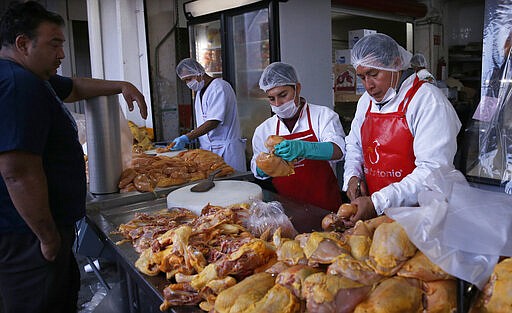 A client waits for his chicken from workers wearing face masks as a precautionary measure amid the spread of the new coronavirus at the &quot;Centro de Abastos,&quot; the main food distribution center in Mexico City, Monday, March 30, 2020. The new coronavirus causes mild or moderate symptoms for most people, but for some, especially older adults and people with existing health problems, it can cause more severe illness or death. (AP Photo/Marco Ugarte)