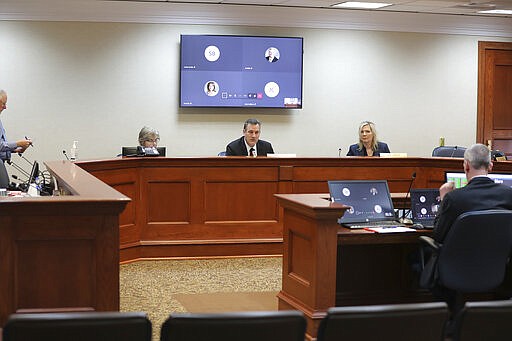 In this photo provided by Patrick Callahan, Senate legislative leaders meet on Monday, March 30, 2020, in the Capitol building in Pierre, S.D. while most lawmakers joined through a teleconference committee. They were considering emergency bills pushed by Gov. Kristi Noem. (Patrick Callahan/South Dakota Broadcasters Association via AP)