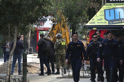 Members of the military and police at the site of an operation on Ermou Street, Athens' main shopping area on Tuesday, March 31, 2020. Police in Greece have cordoned off an area near the country's parliament after workers found what is believed to be a decades-old mortar shell during maintenance on the water mains. (AP Photo/Yorgos Karahalis)