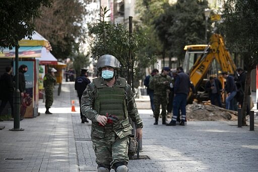 A military officer walks attends an operation at Ermou Street, Athens' main shopping area on Tuesday, March 31, 2020. Police in Greece have cordoned off an area near the country's parliament after workers found what is believed to be a decades-old mortar shell during maintenance on the water mains. (AP Photo/Yorgos Karahalis)