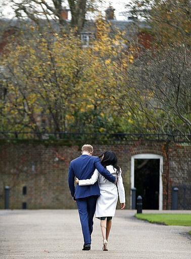 FILE - In this Monday Nov. 27, 2017 file photo Britain's Prince Harry and Meghan Markle walk away after posing for the media in the grounds of Kensington Palace in London. Prince Harry and his wife Meghan are ending their lives as senior members of Britains royal family and starting an uncertain new chapter as international celebrities and charity patrons. In January the couple shocked Britain by announcing that they would step down from official duties, give up public funding, seek financial independence and swap the U.K. for North America. The split becomes official on March 31. (AP Photo/Alastair Grant, File)