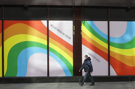 A man wearing a face mask to protect against catching the coronavirus walks past a window display of rainbows in the windows of the famous London department store Harrods in London, Tuesday, March 31, 2020. Rainbows in windows are being used to show hope in the fight against Covid-19, they were first used in Italy with the message 'Tutto andra' bene,&quot; or &quot;Everything will turn out OK,&quot;, the Harrods version reads 'We'llGet Through This Together- Sunnier Days Ahead. (AP Photo/Kirsty Wigglesworth)