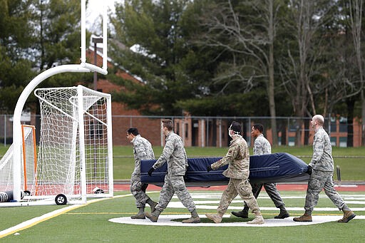 Members of the Connecticut National Guard move sports equipment from a field house to a football and soccer field before unloading supplies for a &quot;surge&quot; hospital that is being constructed to help out during the current coronavirus crisis, Tuesday, March 31, 2020, at Southern Connecticut State University in New Haven. The 250-bed field hospital will facilitate overflow in the event that regional hospitals treating COVID-19 patients reach capacity. (AP Photo/Kathy Willens)