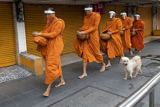 Thai Buddhist monks wear face shields to protect themselves from new coronavirus as they walk to collect alms from devotees in Bangkok, Thailand, Tuesday, March 31, 2020. The new coronavirus causes mild or moderate symptoms for most people, but for some, especially older adults and people with existing health problems, it can cause more severe illness or death. (AP Photo/Sakchai Lalit)