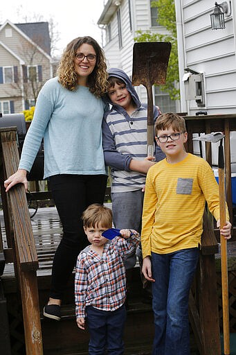 Stephanie Owens and her three children Lucas, 12: Reid, 8; and Cole, 3. Tend to a small garden at their home Wednesday March 25 , 2020, in Glen Allen, Va. Owens is a pharmacist who has had to continue to go to work, but has been able to spend more time with her kids because they are home from school . One of the activities that they have done is planting the garden.  (AP Photo/Steve Helber)