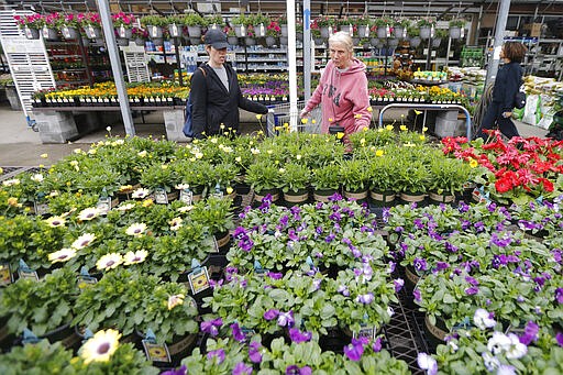 Gail Henrickson, right, and her daughter, Melissa, shop for plants at a local garden center as they stay at home during the coronavirus outbreak Monday March 23 , 2020, in Richmond, Va. The two work at a local restaurant that has closed down and are doing their spring gardening. (AP Photo/Steve Helber)