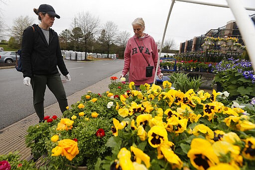 Gail Henrickson, right, and her daughter, Melissa, shop for plants at a local garden center as they stay at home during the coronavirus outbreak Monday March 23 , 2020, in Richmond, Va. The two work at a local restaurant that has closed down and are doing their spring gardening. (AP Photo/Steve Helber)