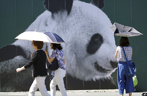 FILE-In this Aug. 22, 2018 file photo people walk with their parasols under the intense sun in Tokyo. Patricia Espinosa, Executive Secretary of the United Nations Framework Convention on Climate Change, on Tuesday chided Japan over its new plan to reduce greenhouse gas emission. Environmental campaigners say Tokyo's new proposal shows no real ambition to increase existing efforts. (AP Photo/Eugene Hoshiko)