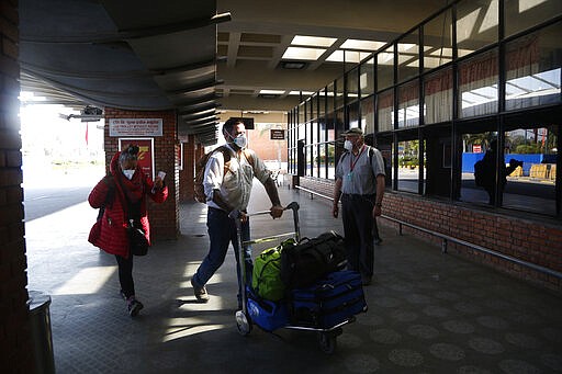 Stranded American citizens arrive to board a Qatar Airways flight at the Tribhuvan International Airport in Kathmandu, Nepal, Tuesday, March 31, 2020. Several American citizens are stranded in Nepal due to the nationwide lockdown enforced in an attempt to stop the coronavirus spread. The new coronavirus causes mild or moderate symptoms for most people, but for some, especially older adults and people with existing health problems, it can cause more severe illness or death. (AP Photo/Niranjan Shrestha)