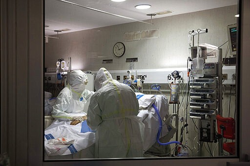 In this photo taken on Friday, March 27, 2020, healthcare workers assist a patience at one of the intensive care units (ICU) at German Trias i Pujol hospital in Badalona, in the Barcelona province, Spain. The new coronavirus causes mild or moderate symptoms for most people, but for some, especially older adults and people with existing health problems, it can cause more severe illness or death. (AP Photo/Anna Surinyach)