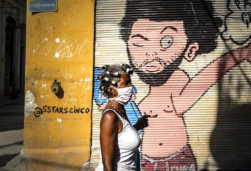 A woman wearing a mask as a precaution against the spread of the new coronavirus walks down the street in Havana, Cuba, Tuesday, March 31, 2020. Cuban authorities are requiring the use of masks for anyone outside their homes. (AP Photo/Ramon Espinosa)