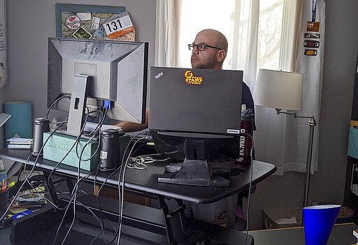 In this March 27, 2020, photo, Eric Bellmore works from his home in Mount Pleasant, Mich., while following a coronavirus-related stay at home guideline. Bellmore, who considers himself an extrovert, says it's been a struggle to adjust to a world where social interaction is highly limited. (Photo/Eric Bellmore)