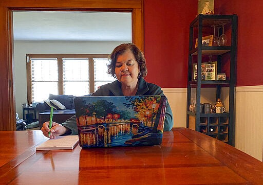 In this March 27, 2020, photo, Lisa Kaenzig, dean of William Smith College, works from her home while following coronavirus Stay-at-Home guidelines in Geneva, N.Y. The world generally has been a place where extroverts are rewarded and introverts get a side-eye, says Kaenzig. &quot;All of the things that make the world harder for them as introverts, the world is better for them right now. They're adapting much more quickly,&quot; she says. (Morgan Kaenzig de Denus via AP)