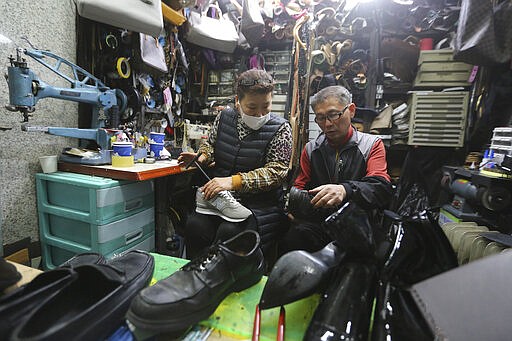 In this March 25, 2020 photo, South Korean shoe repairman Kim Byung-rok and his wife Kwon Jeom-deuk work at their shop in Seoul, South Korea.  Kim is in news after he revealed plans to donate his property to help support people facing economic difficulties amid the coronavirus outbreak. Kim says he wants to donate parts of his land on a small mountain near the border with North Korea that he bought in 2014.(AP Photo/Ahn Young-joon)