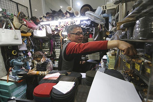 In this March 25, 2020 photo, South Korean shoe repairman Kim Byung-rok and his wife Kwon Jeom-deuk work at their shop in Seoul, South Korea. Kim is in news after he revealed plans to donate his property to help support people facing economic difficulties amid the coronavirus outbreak. Kim says he wants to donate parts of his land on a small mountain near the border with North Korea that he bought in 2014.(AP Photo/Ahn Young-joon)