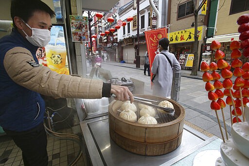 A man wearing face masks to protect against the spread of the new coronavirus waits for customers at Yokohama China Town near Tokyo, Tuesday, March 31, 2020. As the the spread of the coronavirus continues, Japan has extended its highest travel warnings to 49 countries, including the United States, Canada and Britain, as well as all of China and South Korea. (AP Photo/Koji Sasahara)