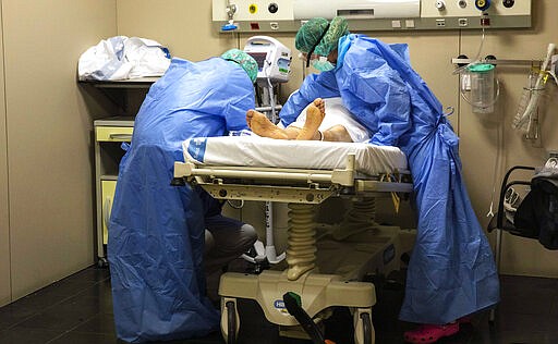 In this photo taken on Friday, March 27, 2020, healthcare workers assist a patient at one of the intensive care units (ICU) at German Trias i Pujol hospital in Badalona, in the Barcelona province, Spain. The new coronavirus causes mild or moderate symptoms for most people, but for some, especially older adults and people with existing health problems, it can cause more severe illness or death. (AP Photo/Anna Surinyach)