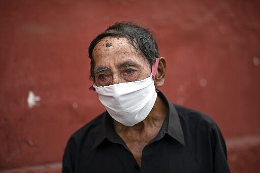 Ciro Orlando Gijon, 78, wearing a protective face mask as a precaution against the spread the new coronavirus, waits to apply for shelter at the Plaza de Toros de Acho bullring, in Lima, Peru, Tuesday, March 31, 2020.  The mayor of Lima reported that the plaza will provide shelter and balanced meals for some of the city's homeless amid the new coronavirus pandemic. (AP Photo/Rodrigo Abd)