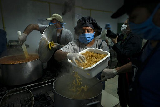 Cooks prepare pasta at a soup kitchen at the San Cayetano church in Jose Leon Suarez neighborhood on the outskirts of Buenos Aires, Argentina, Tuesday, March 31, 2020. The Argentine government said Tuesday that the number of people requesting food assistance has increased following the lockdowns that have left many people unable to work amid the COVID-19 pandemic.  (AP Photo/Victor R. Caivano)