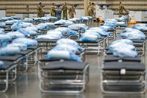 Members of the Texas Army National Guard unpack crates of supplies as they set up a field hospital in response to the new coronavirus pandemic at the Kay Bailey Hutchison Convention Center on Tuesday, March 31, 2020, in Dallas. (Smiley N. Pool/The Dallas Morning News via AP, Pool)