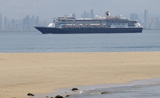 The Zaandam cruise ship, carrying dozens of guests with flu-like symptoms, arrives to the bay of Panama City, seen from Isla de Taboga, Panama, Friday, March 27, 2020, amid the worldwide spread of the new coronavirus. Once the vessel reaches Panamanian waters, health authorities are expected to board the ship to test passengers and decide whether it can cross the Panama Canal to head on towards Fort Lauderdale. (AP Photo/Arnulfo Franco)