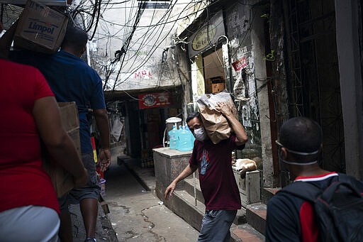 Local volunteers carries packages with soap and detergent to be distributed in an effort to avoid the spread of the new coronavirus in the Rocinha slum of Rio de Janeiro, Brazil, Tuesday, March 24, 2020. (AP Photo/Leo Correa)