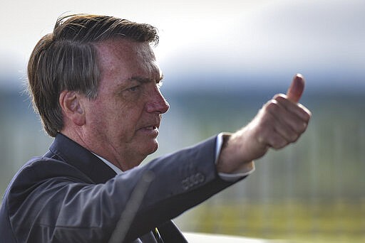 Brazil's President Jair Bolsonaro greets supporters and journalists as he arrives to give a news conference on the new coronavirus at Planalto presidential palace in Brasilia, Brazil, Friday, March 27, 2020. Even as coronavirus cases mount in Latin America&#146;s largest nation, Bolsonaro is calling the pandemic a momentary, minor problem and saying strong measures to contain it are unnecessary. (AP Photo/Andre Borges)