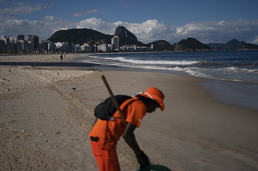 Gloria Maria cleans the shore of an unusually empty Copacabana beach backdropped by the Sugar Loaf Mountain in Rio de Janeiro, Brazil, Thursday, March 26, 2020, as people stay indoors to help contain the spread of the new coronavirus. The 41-year-old city worker said that in her 10 years of work cleaning the beach, she never saw an empty beach on a sunny Thursday. &quot;It's terrible, people are dying in Europe due this virus,&quot; she added. (AP Photo/Leo Correa)