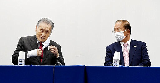 In this March 30, 2020, photo, Tokyo 2020 Organizing Committee President Yoshiro Mori, left, and Toshiro Muto, right, CEO of the Tokyo 2020 Organizing Committee, wear face masks during a news conference, in Tokyo Monday, March 30, 2020.  The countdown clock is ticking again for the Tokyo Olympics. They will be July 23 to Aug. 8, 2021. This seems light years away, but also small and insignificant compared to the worldwide fallout from the coronavirus. (Kyodo News via AP)