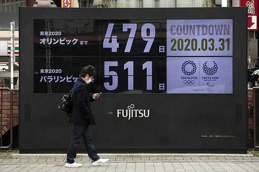 A man walks past a countdown display for the Tokyo 2020 Olympics and Paralympics Tuesday, March 31, 2020, in Tokyo. The countdown clock is ticking again for the Tokyo Olympics. They will be July 23 to Aug. 8, 2021. The clock read 479 days to go. This seems light years away, but also small and insignificant compared to the worldwide fallout from the coronavirus.  (AP Photo/Jae C. Hong)