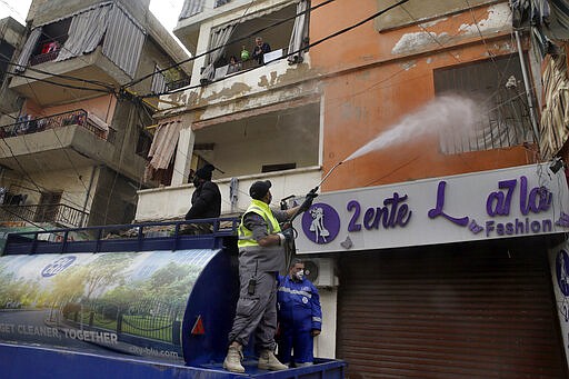 In this Friday, March 27, 2020 photo, members of the Islamic Health Society, an arm of the Iran-backed militant Hezbollah group spray disinfectant in a southern suburb of Beirut, Lebanon. Hezbollah has mobilized the organizational might it once deployed to fight Israel or in Syria's civil war to battle the spread of the novel coronavirus. It aims to send a clear message to its Shiite supporters that it is a force to rely on in times of crisis -- particularly after it suffered a series of blows to its prestige. (AP Photo/Bilal Hussein)
