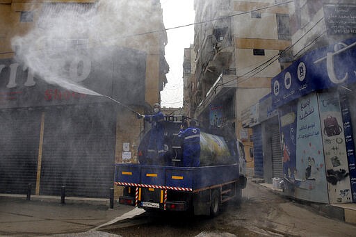 In this Friday, March 27, 2020 photo, members of the Islamic Health Society, an arm of the Iran-backed militant Hezbollah group sprays disinfectants as a precaution against the coronavirus, in a southern suburb of Beirut, Lebanon. Hezbollah has mobilized the organizational might it once deployed to fight Israel or in Syria's civil war to battle the spread of the novel coronavirus. It aims to send a clear message to its Shiite supporters that it is a force to rely on in times of crisis -- particularly after it suffered a series of blows to its prestige. (AP Photo/Bilal Hussein)