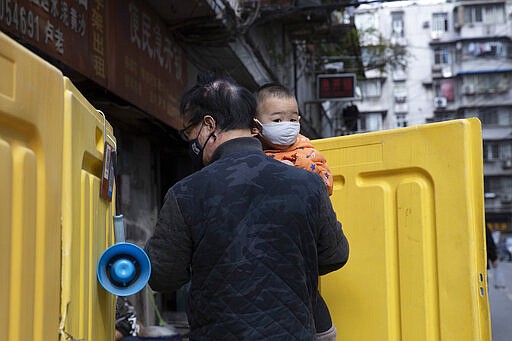 A child is carried between yellow barriers used to seal off a neighborhood in Wuhan in central China's Wuhan province on Wednesday, April 1, 2020. Skepticism about China&#146;s reported coronavirus cases and deaths has swirled throughout the crisis, fueled by official efforts to quash bad news in the early days and a general distrust of the government. In any country, getting a complete picture of the infections amid the fog of war is virtually impossible. (AP Photo/Ng Han Guan)